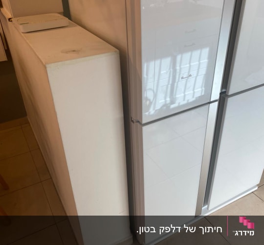 קיר מחיצה נמוך צבוע לבן לצד מקרר במטבח